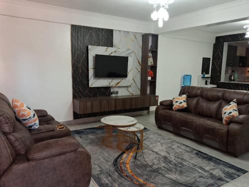 - un salon avec deux canapés bruns et une télévision dans l'établissement Moonshine walkers furnished apartments, à Naivasha