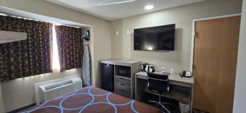 a hotel room with a bed and a desk and a television at Super 8 by Wyndham San Antonio Downtown NE in San Antonio