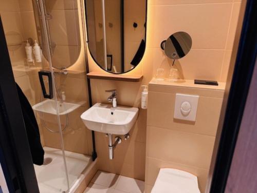 a small bathroom with a sink and a mirror at Hotel Astor Kiel by Campanile in Kiel