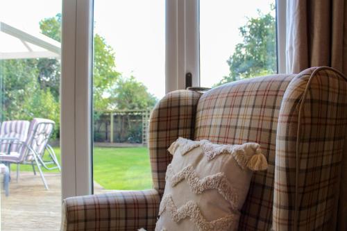 ein kariertes Sofa mit einem Kissen und einem Fenster in der Unterkunft Spacious 3-Bed Bungalow with Parking in Pensby by Rework Accommodation in Birkenhead