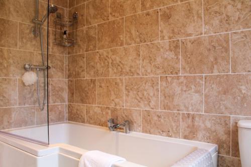 ein Badezimmer mit Badewanne und Dusche in der Unterkunft Spacious 3-Bed Bungalow with Parking in Pensby by Rework Accommodation in Birkenhead