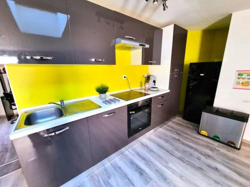 a kitchen with a sink and a yellow wall at Spacieux de 150 m idéal familles et groupes in Elbeuf