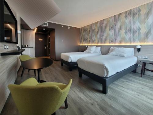 a hotel room with two beds and a table and chairs at Novotel Arica in Arica
