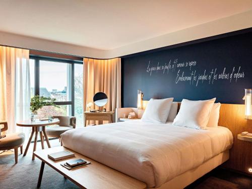 a bedroom with a large bed with a writing on the wall at Domaine de la Reine Margot Paris-Issy - MGallery Collection in Issy-les-Moulineaux