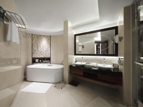 a bathroom with a tub and a sink and a bath tub at Pullman Haikou in Haikou