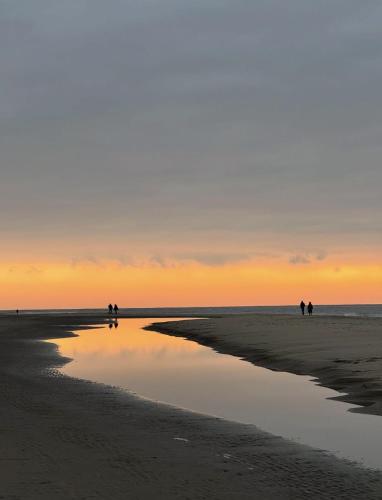 a group of people walking on the beach at sunset at TEAM bnb in De Koog