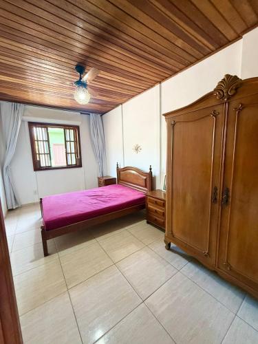 a bedroom with a pink bed and a wooden cabinet at Meu Refúgio Praia Seca in Araruama
