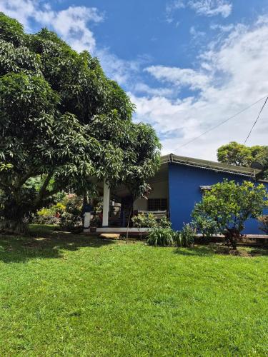 a house with a blue building and a yard at Casa rustica y familiar con piscina en La Vega Cund in La Vega