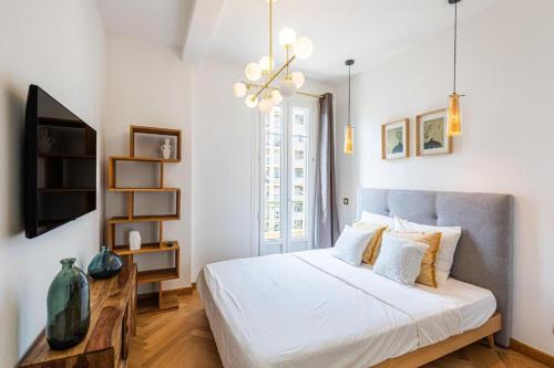 a bedroom with a large white bed and a chandelier at Appartement Prestige sur la Promenade des Anglais in Nice