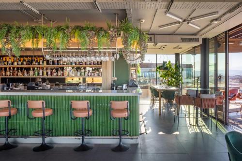 a restaurant with a green bar with chairs at The Social Hub Florence Lavagnini in Florence