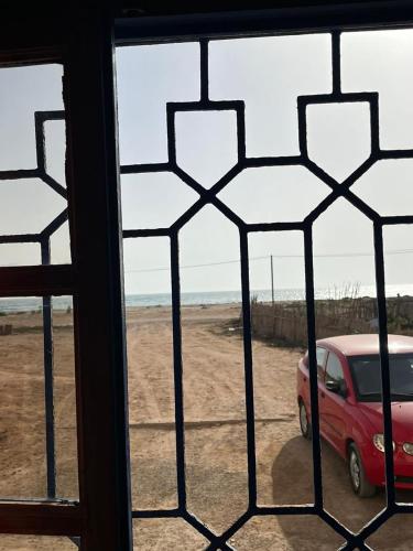 a window view of a red car parked in a field at Banana surf town in Tamraght Ouzdar