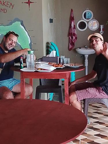 two men sitting at a table in a restaurant at Three Ken Homestay & Cafe in Manado