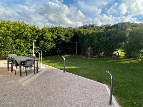 un patio con tavolo e sedie in un parco di Maison avec vue mer à Omaha Beach - idéal familles a Saint-Laurent-sur-Mer