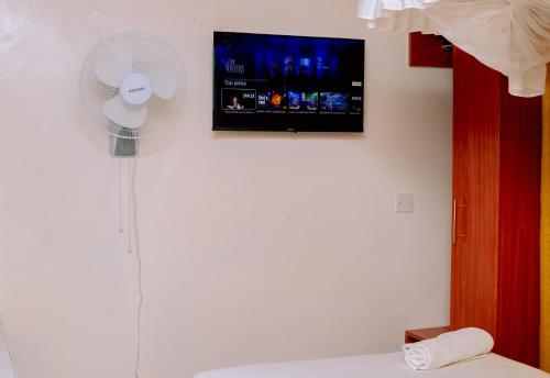 a room with a fan and a tv on a wall at Studio apartment in Kisumu