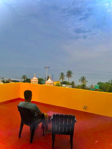 a man sitting in a chair on a balcony at Virtus Villa in Puducherry