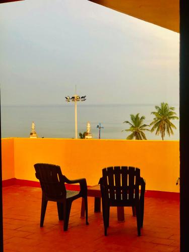 two chairs and a table in front of a yellow wall at Virtus Villa in Puducherry