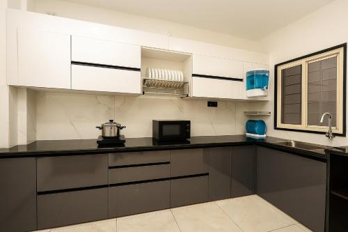 a kitchen with white cabinets and a black counter top at Home Escape Azure 3BHK Bunglow Near Apollo DB City in Indore