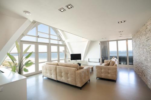 a living room with two couches and a tv at Poort Beach Boutique Apartments in Bloemendaal Aan Zee