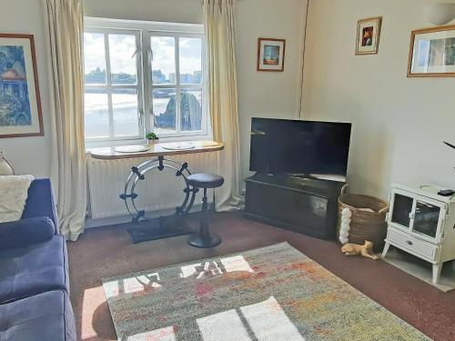 Una sala de estar con un sofá azul y un televisor. en Cerdd Y Mor, en Tenby