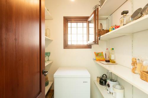 baño pequeño con nevera blanca y ventana en New! Villa Can Gibert, en Sant Mateu d’Albarca