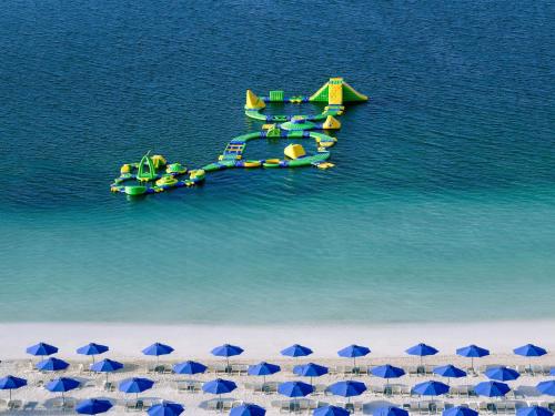 an aerial view of a beach with blue umbrellas at Mövenpick Resort Al Marjan Island in Ras al Khaimah