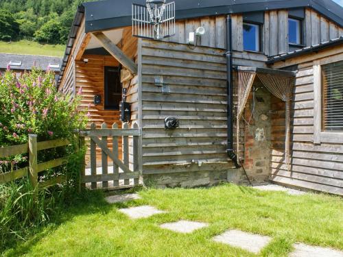 a wooden cabin with a gate and a fence at Llety'r Saer in Pen-y-bont-fawr