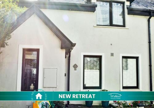 Una casa blanca con un nuevo cartel de retiro frente a ella. en Skellig Fuchsia Lodge Ballinskelligs by Trident Holiday Homes, en Dungeagan