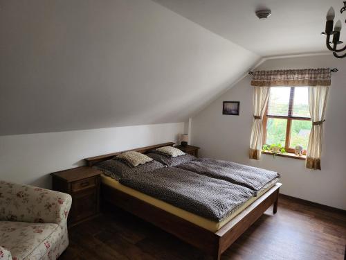 a bedroom with a bed and a chair and a window at Hospůdka Na Trucovně in Sázava