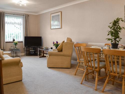 a living room with a table and chairs and a television at Swallow Cottage - Uk49756 in Little Singleton