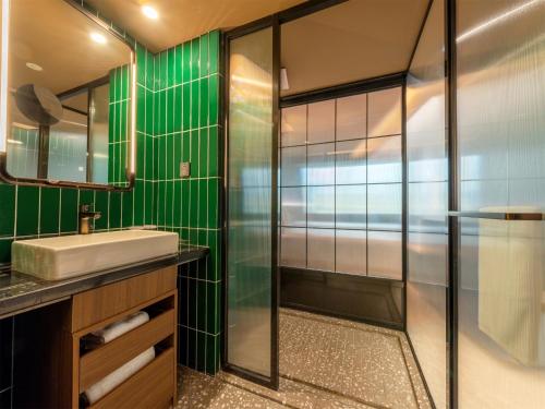 a green bathroom with a sink and a shower at Orange Hotel Guangzhou Ouzhuang Subway Station in Guangzhou