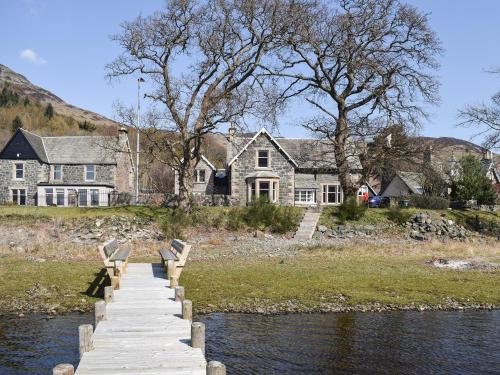 a wooden dock with benches in front of a house at Lochearnside Lodge in Saint Fillans
