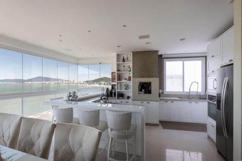 cocina con electrodomésticos blancos y ventana grande en Apto Frente Mar Itapema Canto da Praia, en Itapema