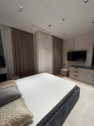 a bedroom with a large bed and a flat screen tv at Nest One Luxe, Элитные апартаменты с балконом и видом на фонтан Tashkent City Park 110 in Tashkent
