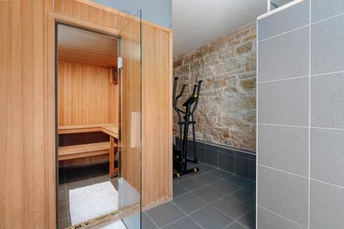 a bathroom with a walk in shower next to a stone wall at Villa Radetici in Radetići