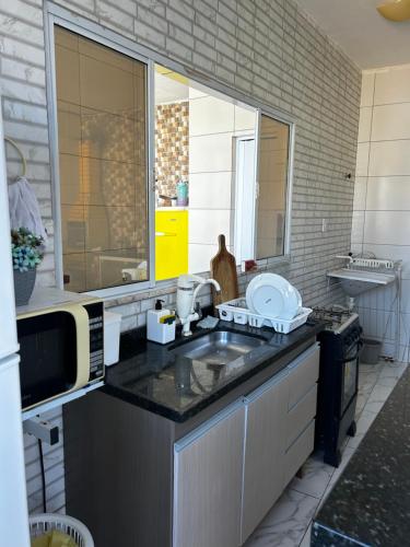 a kitchen with a sink and a microwave at Casa com piscina e Ar condicionado in Camaçari