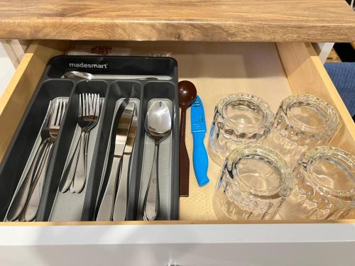 een houten lade met daarin bestek en glazen bij Charlottetown brand-new suite in Charlottetown