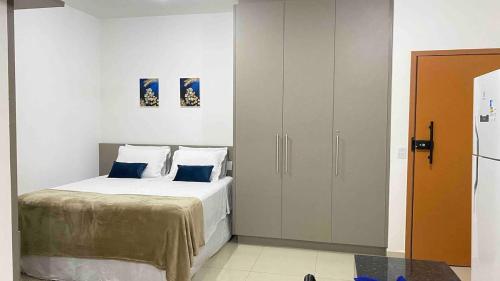 a bedroom with a white bed with blue pillows at 308-1 · Suíte Luxo Unievangélica/Ânima. 308 in Anápolis