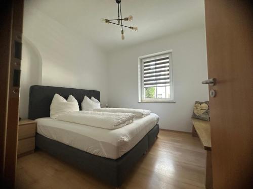 a bedroom with a bed with white sheets and a window at Haus Alpina in Garmisch-Partenkirchen