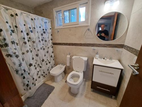 a man taking a picture of a bathroom with a toilet and sink at Amura in Mar Azul