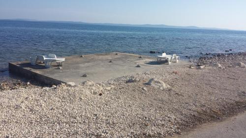 un grupo de sillas y mesas en un muelle en el agua en Apartments Batovanja en Vir