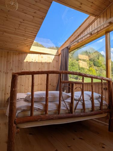 a bed in a room with a large window at Ecohouse Svaneti in Mestia