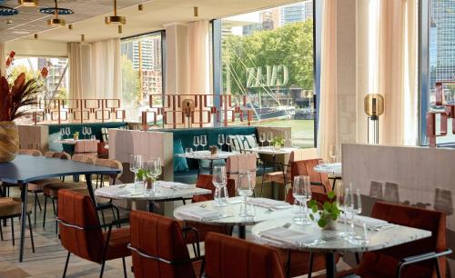 a restaurant with tables and chairs and windows at DoubleTree by Hilton Rotterdam Centre in Rotterdam