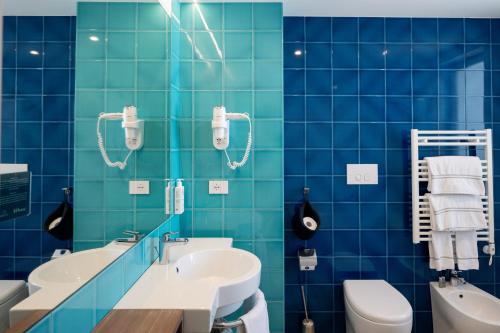 a blue tiled bathroom with a sink and a toilet at Hotel Riva Del Sole in Giovinazzo