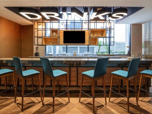 a kitchen with a large bar with blue chairs at ibis Bengaluru Hebbal - An Accor Brand in Bengaluru