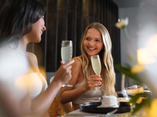 a woman is holding a glass of champagne at Grand Mercure Bali Seminyak in Seminyak