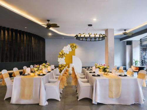 a banquet hall with white tables and white chairs at Grand Mercure Bali Seminyak in Seminyak