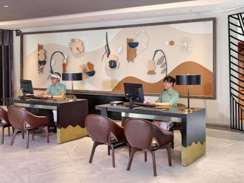 two women sitting at tables with computers in a lobby at Grand Mercure Bali Seminyak in Seminyak
