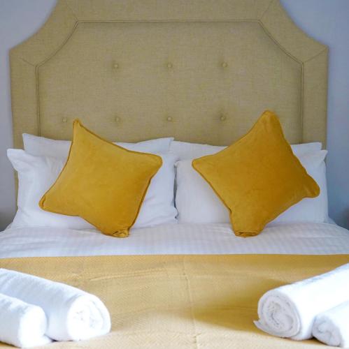 a bed with two yellow pillows on it at The Hart Uttoxeter in Uttoxeter