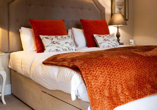 a bedroom with a large bed with red and white pillows at The Hart Uttoxeter in Uttoxeter