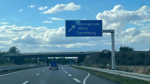 a car driving down a highway with a blue sign at D1 - Klein aber fein in Wernigerode